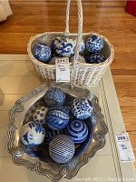 Wicker basket holding ceramic balls and silver-toned bowl filled with additional balls on coffee table