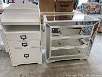 Photo showing both the white filing cabinet with organizer and the mirrored three-drawer cabinet side by side in garage area.
