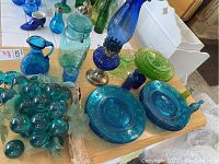 Overview of blue and green glassware including the glass grapes, blue plates, and hurricane lamp