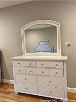 Front view of white dresser with attached arched mirror showing 10 drawers and round metal knobs
