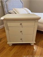 Front view showing three drawers with round metal knob pulls and cream/off-white finish.