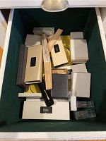 Open drawer containing multiple boxed items including Cross brand pens and others