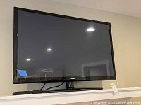Front view of the Samsung 43-inch flatscreen TV mounted on a stand with remote included, showing the screen and bezel.