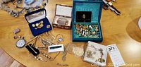 Overview of collection showing cufflinks in blue box, medallions, tie clips and other assorted pieces on table surface.