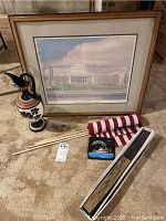 Full view showing all items in the lot including framed lithograph, ceramic pitcher, folded flags, small fan box, and New Orleans art