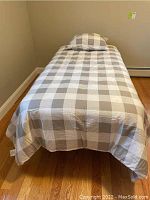 Assembled twin bed showing comforter and pillow on metal frame