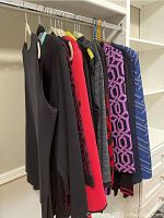 Rack of seven women's Misook brand tops, jackets, and sweaters in various colors including black, red, purple, and blue with different patterns.