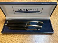 Three Aldo Domani pens in a blue velvet interior box with Aldo Domani Limited branding on the inside lid.