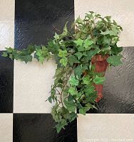 Wall sconce mounted on wall with faux ivy vines cascading down.