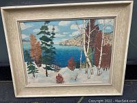 Full view of framed oil painting showing a winter landscape with trees and a lake or river under a partly cloudy sky.
