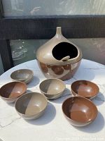 Mid Century Modern plastic snack set from Japan showing the full set on a white marbled table with natural light. The set includes the covered bowl with lid and matching spoon, surrounded by six small bowls.