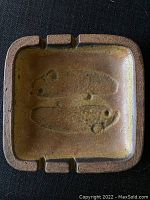 Top-down view of square ashtray with fish imprints and cigarette rests