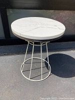 Full side view of the round quartzite top side table on metal wireframe base.