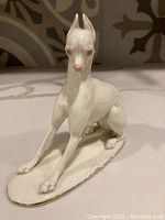 Front view of the porcelain dog figurine, showing its posture, facial features and gloss finish.