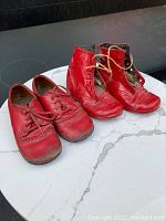 Two pairs of vintage-style red children's shoes, one low cut and one high-top boot