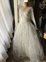 Front full view of vintage wedding dress on mannequin showing lace overlay, long lace sleeves, and flowing tulle skirt.