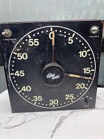 Front view of the vintage black photography timer clock showing dial with numbers 0 to 60, central knob labeled 'Crl LAB', and toggle switches for TIME/FOCUS and ON/OFF.