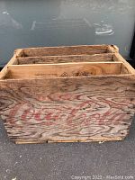 Side view of the vintage wooden crate with faded red Coca Cola lettering.