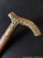 Close-up of the brass handle with detailed engraved patterns and signs of aging.