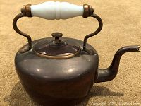 Front angle view showing the rounded copper kettle with brass lid rim and white glass handle