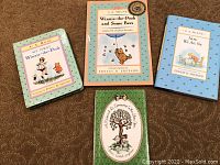Four hardcover books by A.A. Milne and Joan Walsh Anglund, including 'My First Winnie-the-Pooh,' 'Winnie-the-Pooh and Some Bees,' 'Now We Are Six,' and 'A Friend is Someone Who Likes You' with detailed covers.