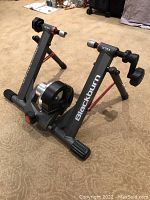 Blackburn Ultra bike trainer angled view showing resistance unit, frame, and adjustment components on carpet floor.