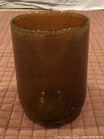 Side view of amber-coloured blown glass wine cooler showing its textured surface with tiny bubbles and heavy structure.