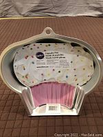 Front view of Wilton cupcake design cake pan including cupcake liners and paperwork inside the pan.