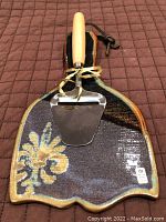 Full view of the ceramic cheese tray with attached cheese slicer on a brown quilted surface