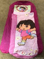 Top-down view showing Dora the Explorer graphic on the inflatable bed's sleeping bag, and the headrest with Dora and Boots.