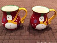 Front view of two hand-painted Christmas ceramic mugs with snowman design