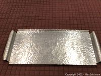 Top view of MCM zinc serving tray showing hammered pebbled surface and raised rolled edges