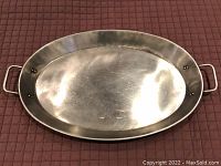 Metal oval serving tray with visible minor surface scratches and knife marks, viewed from above to show surface and handles.