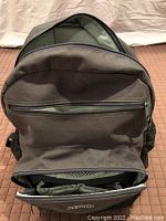 Front view of brown Peg Perego baby knapsack showing zippered compartments