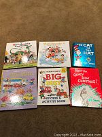 Six oversized children's books arranged on floor, front covers visible showing titles and authors as described.