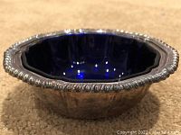 Side view of silver plated candy dish showing ornate filigree edge and cobalt glass insert.