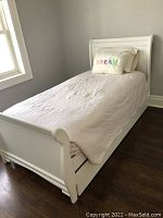 White sleigh bed fully assembled with pale bedding and DREAM pillow