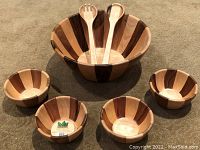Full salad set arranged showing large wooden bowl, four small bowls, and two utensils on carpeted surface.