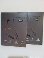 Two boxed Arespark AP-12 magnetic waterproof neckband style headsets with long battery life shown in original packaging.