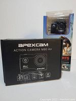 Photo showing Apexcam Action Camera M80 Air box in black with product details and a second packaged Full HD sports camera in blister pack.