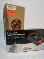 Image showing cardboard box with Adam's Polishes logo and packaging of a 12V 8A - 24V 4A Pulse Repair Battery Charger.