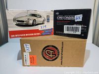 Three boxed items: car MP3 player, HD car camera, and Adam's Polishes product box.