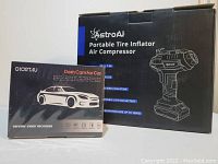 Photo showing boxed Chortau dash cam and boxed AstroAI portable tire inflator air compressor against white background.