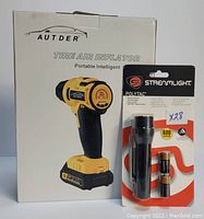 Photo showing Autder tire air inflator box and Streamlight Polytac flashlight package including batteries.