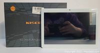 Photo of the Kisedar 10 inch Android tablet in white and silver alongside its original box showing 64GB storage.