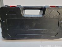 Black plastic carrying case with handle and red latches closed, showing front view.