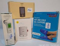 Photo showing the four main items in the lot: forehead thermometer, TENS device box, rapid relief gel slippers box, and mini humidifier box.