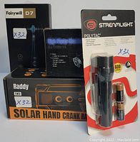 Front view of boxed and packaged survival items including flashlight, headlamp, solar hand crank radio, and electric toothbrush.