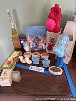 Photo showing various Avon perfume bottles including a red couple figurine and a blue gnome, plus boxed and loose soaps and collectibles.