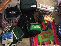 Wide angle photo showing multiple bags including cooler bags and various tote bags spread out on a carpeted floor.
